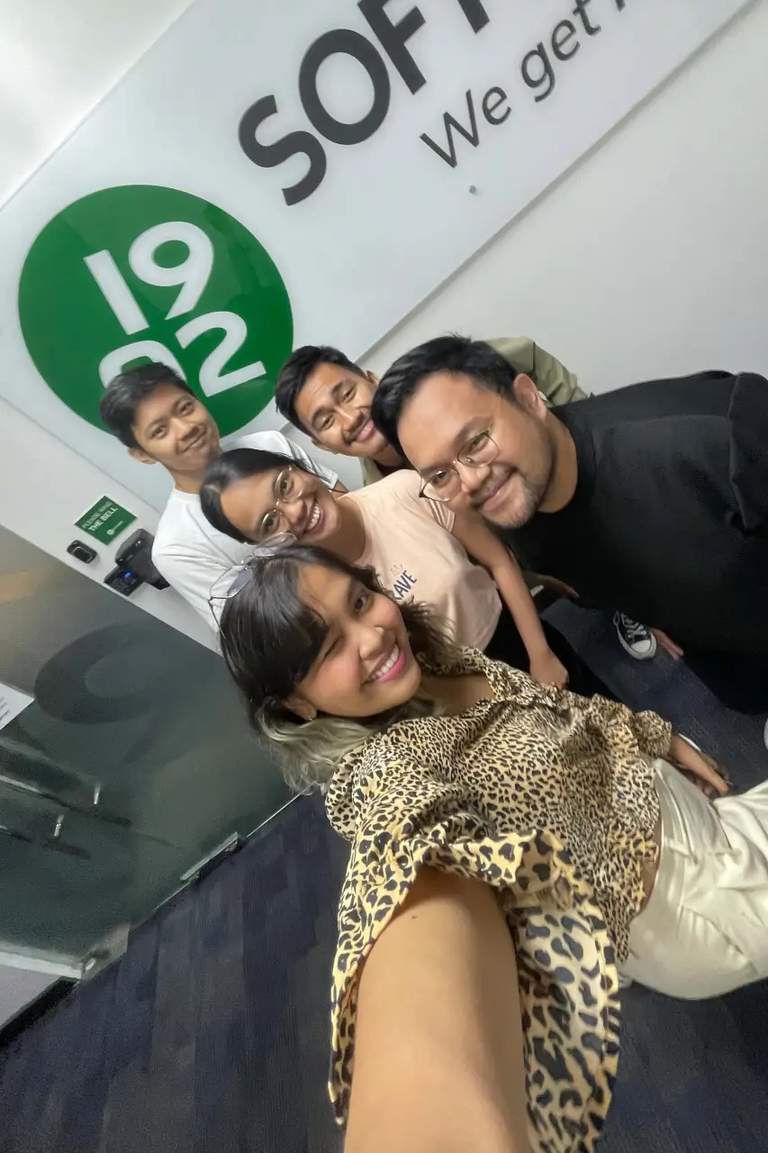 Group selfie of five people inside 1902 Software office under company logo on National Selfie Day.